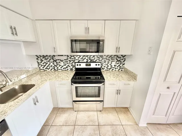 a kitchen with granite countertop a stove a sink and a microwave