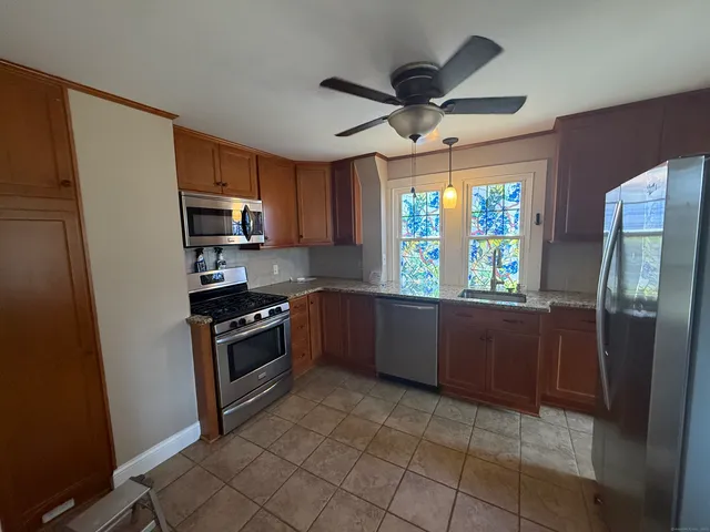 a kitchen with stainless steel appliances granite countertop a refrigerator a sink dishwasher a stove top oven a window and a dining table