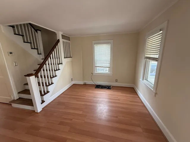 a view of an empty room with wooden floor fireplace and a window