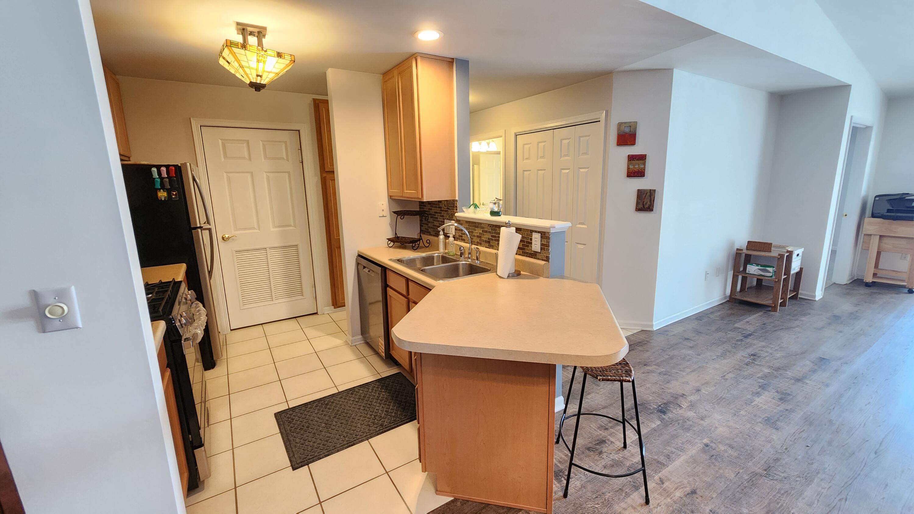 604 Cambridge Court, Unit 2A Munster, IN 46321 - Photo 6 of 31 a kitchen with stainless steel appliances kitchen island a table chairs in it and wooden floors