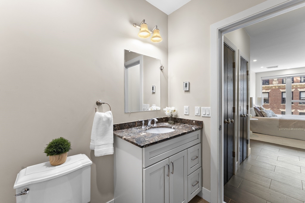 99-105 Broad Street, Unit 8B Boston, MA 02110 - Photo 22 of 37 a bathroom with a granite countertop sink and a mirror