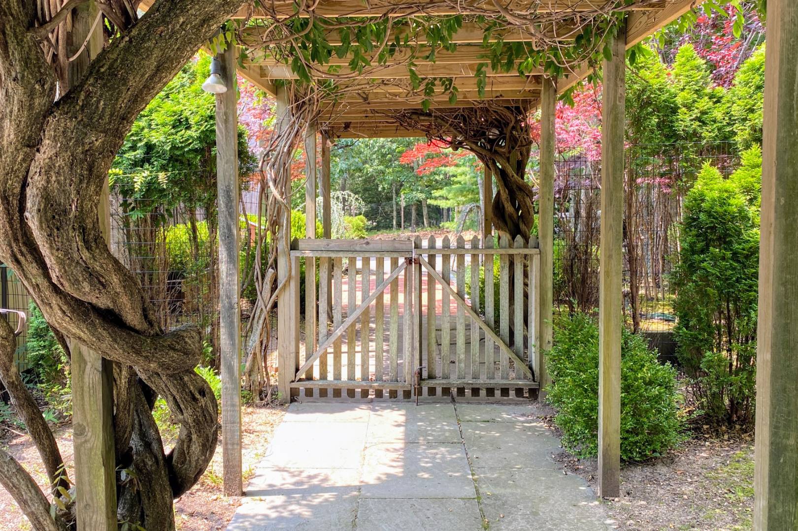 30 Wheelock Walk East Hampton, NY 11937 - Photo 13 of 15 a view of a pathway of a building with large tree and wooden fence