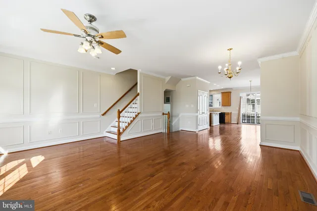 a view of an empty room with wooden floor and a ceiling fan