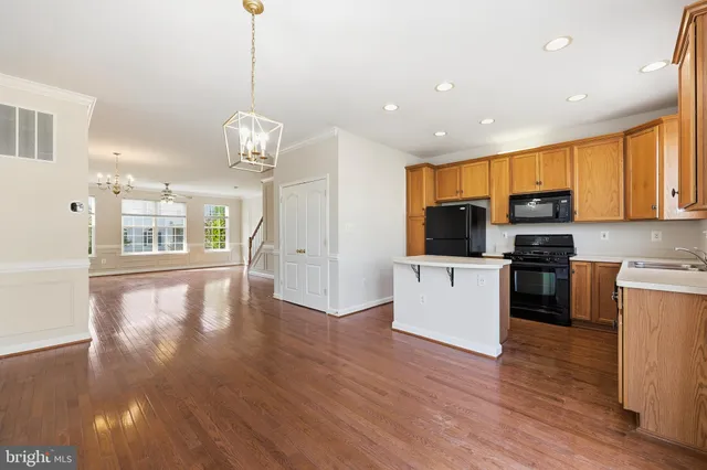 a kitchen with stainless steel appliances granite countertop a refrigerator a stove top oven a sink dishwasher and white cabinets with wooden floor