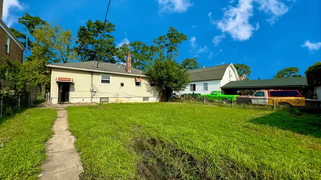 a view of a white house with a big yard and large tree