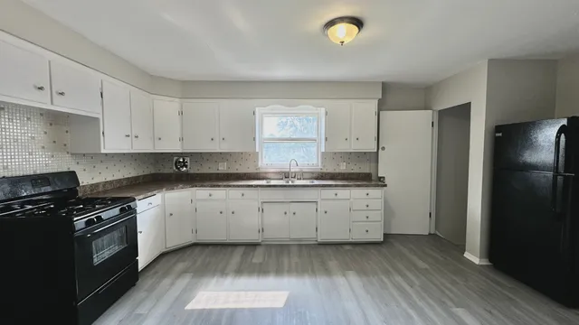 a kitchen with granite countertop a stove a sink and a refrigerator