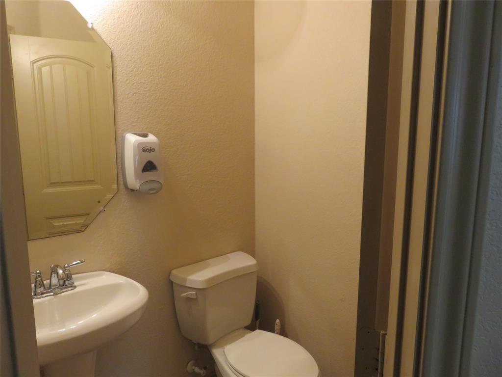 1122 Walter Stephenson Road Midlothian, TX 76065 - Photo 5 of 26 Pedestal sink with chrome fixtures, an octagonal mirror, and a white toilet