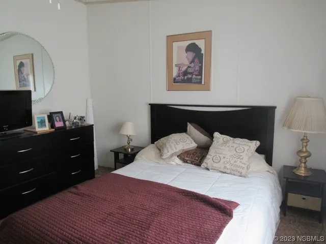 a bedroom with a bed and a lamp on dresser