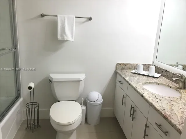 a bathroom with a granite countertop toilet and a sink