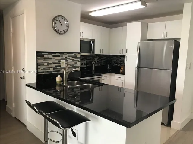 a kitchen with granite countertop a refrigerator a stove top oven and a sink