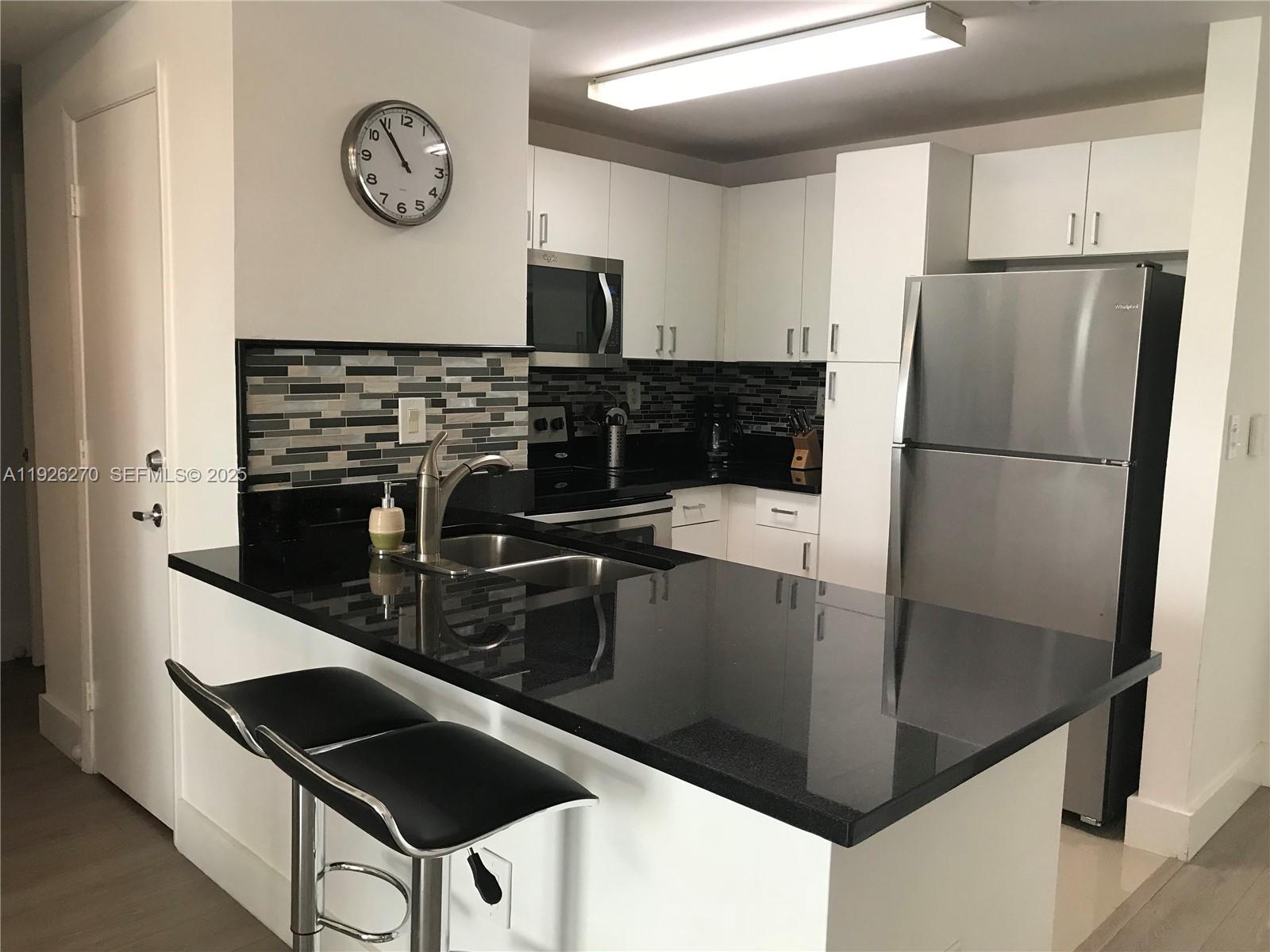 185 Southeast 14th Terrace, Unit 802 Miami, FL 33131 - Photo 7 of 19 a kitchen with granite countertop a refrigerator a stove top oven and a sink