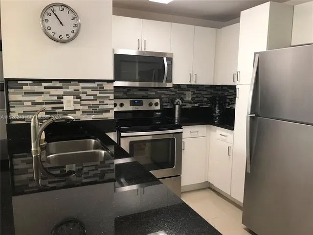 a kitchen with a refrigerator and a stove top oven