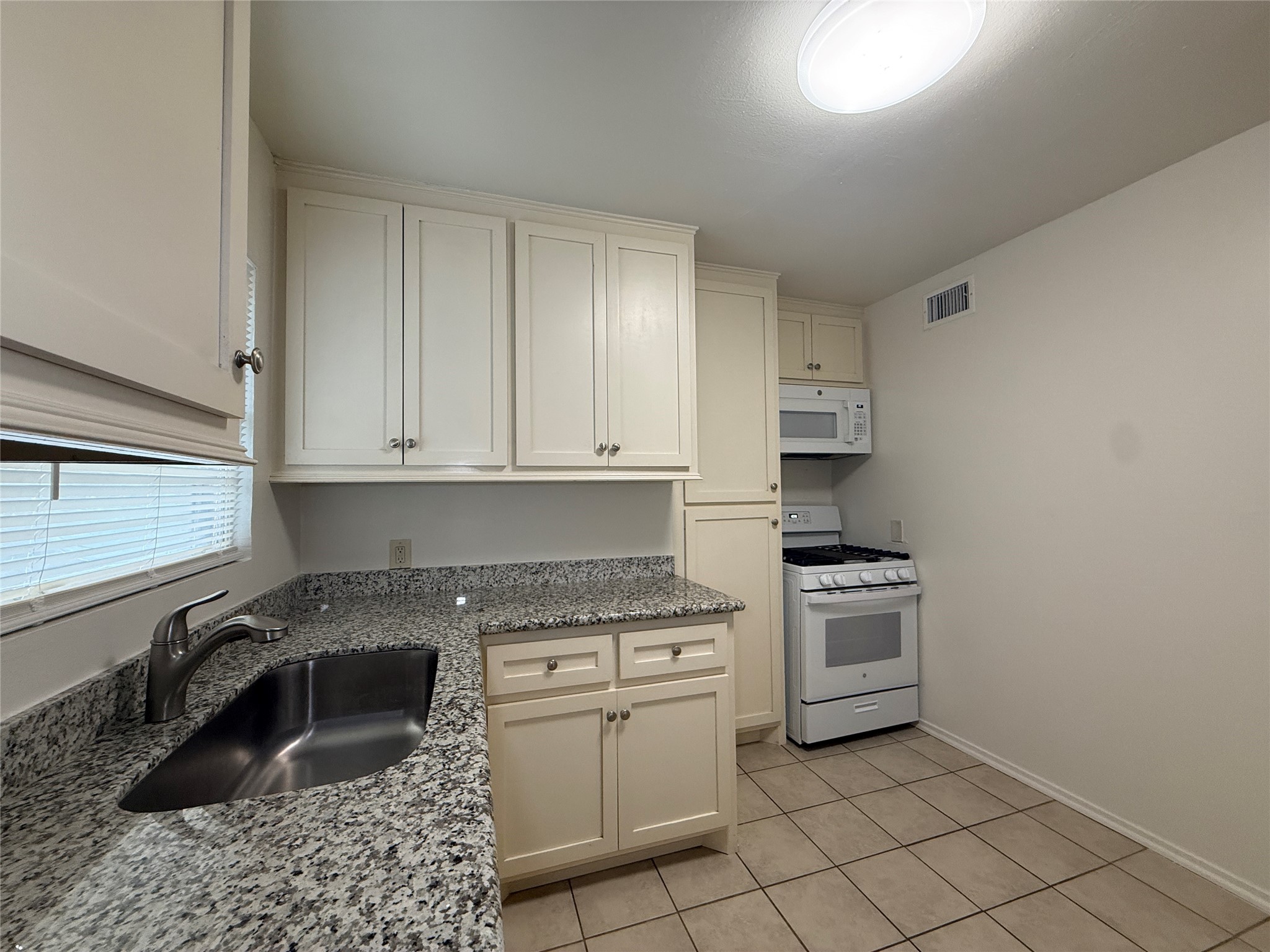 1318 Heights Boulevard, Unit 4 Houston, TX 77008 - Photo 9 of 21 a kitchen with granite countertop a sink stove and cabinets