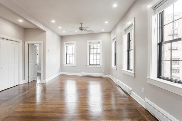 a view of an empty room with wooden floor and a window