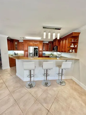 a room with stainless steel appliances kitchen island granite countertop a sink and a cabinets