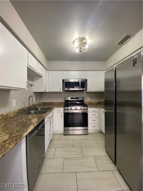 1722 East University Avenue, Unit 8 Las Vegas, NV 89119 - Photo 4 of 28 Kitchen with stainless steel appliances, dark stone counters, white cabinetry, and light tile patterned flooring
