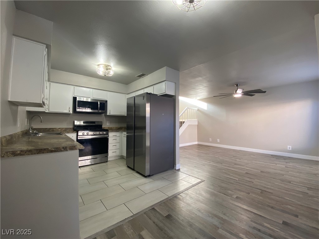1722 East University Avenue, Unit 8 Las Vegas, NV 89119 - Photo 6 of 28 Kitchen featuring appliances with stainless steel finishes, light wood-type flooring, dark countertops, white cabinets, and ceiling fan