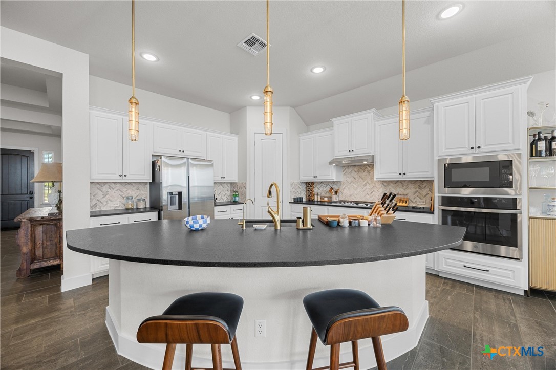 109 High Plains Drive Georgetown, TX 78628 - Photo 8 of 43 a kitchen with stainless steel appliances granite countertop a dining table chairs sink refrigerator and microwave