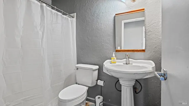 a bathroom with a sink a toilet and mirror