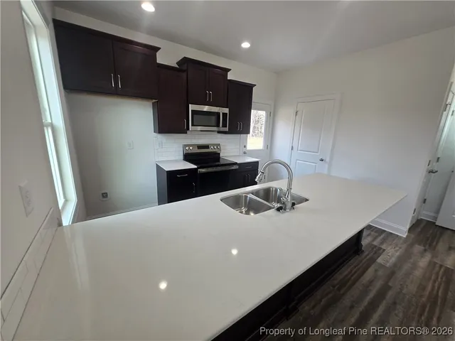 a kitchen with stainless steel appliances a sink dishwasher a stove top oven a refrigerator and cabinets