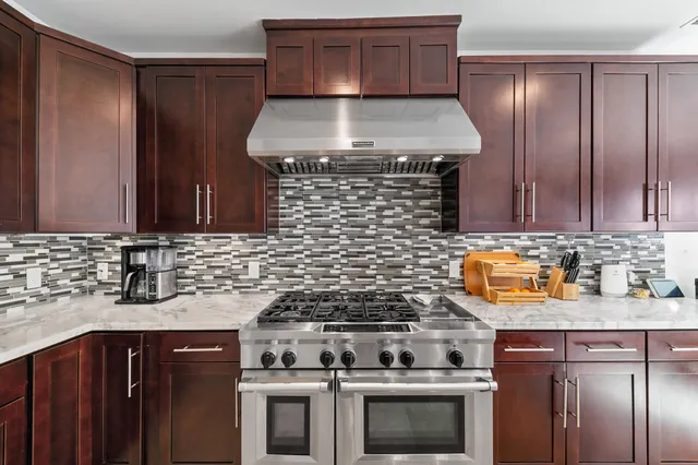 a kitchen with granite countertop a stove top oven cabinetry a sink and a refrigerator