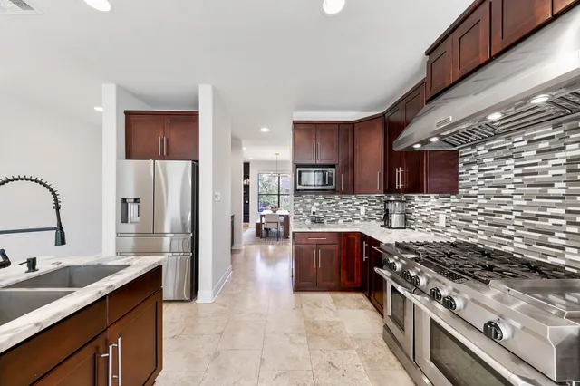 a large kitchen with stainless steel appliances granite countertop a stove a sink dishwasher and a refrigerator