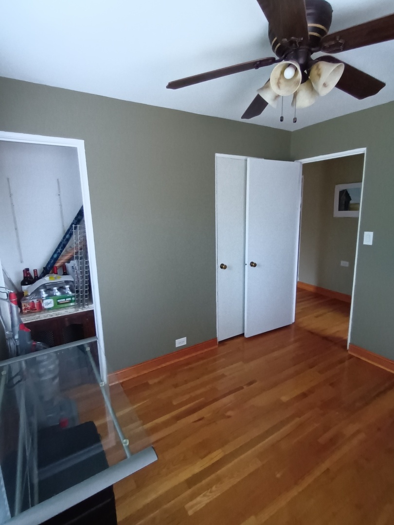 8742 East Prairie Road Skokie, IL 60076 - Photo 12 of 29 a view of an empty room with a ceiling fan and wooden floor