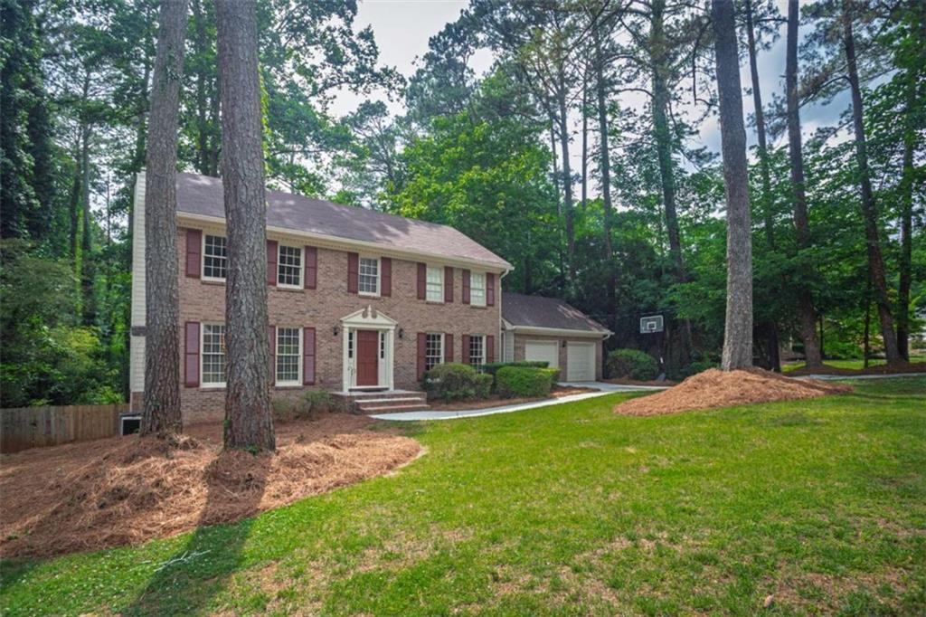 3838 Hunting Ridge Drive Southwest Lilburn, GA 30047 - Photo 3 of 56 a front view of a house with a garden and trees