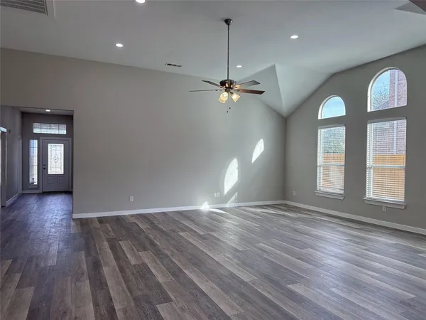 an empty room with wooden floor chandelier and glass door