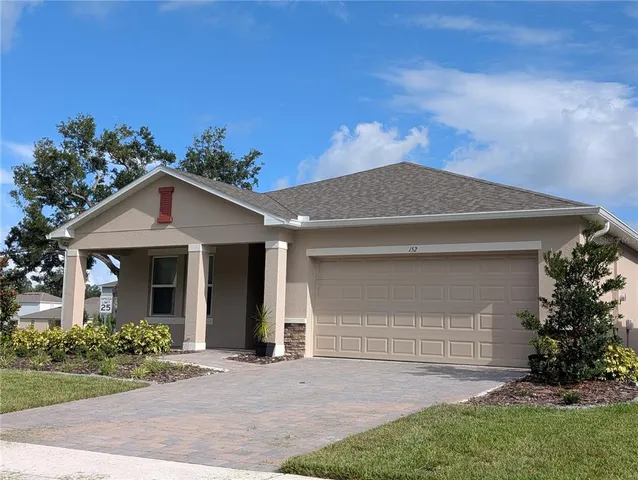 a view of a house with a yard and potted plants