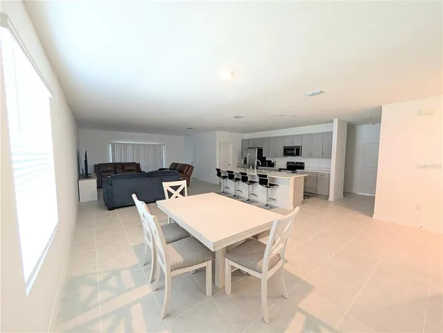 a kitchen with a dining table chairs and refrigerator