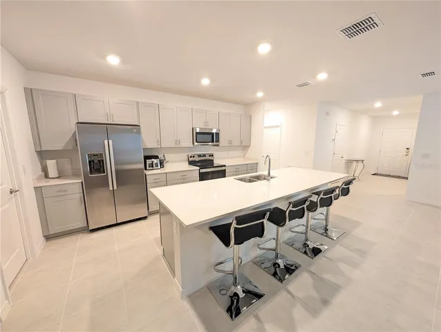a kitchen with stainless steel appliances a sink a stove a refrigerator with white cabinets and wooden floor