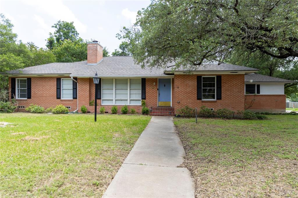 3228 Colcord Avenue Waco, TX 76707 - Photo 2 of 29 Brick exterior featuring a light blue entry door, black window shutters, a front walkway, a covered porch, and a mature tree
