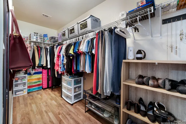 a view of walk in closet with clothes and shoes