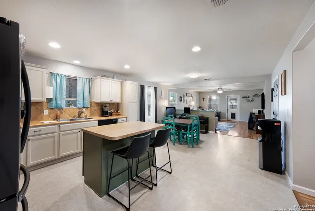 a kitchen with stainless steel appliances kitchen island granite countertop a table chairs sink and cabinets