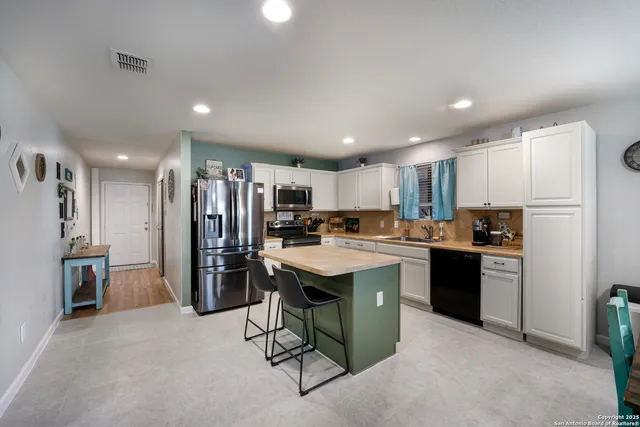 a kitchen with refrigerator and chairs