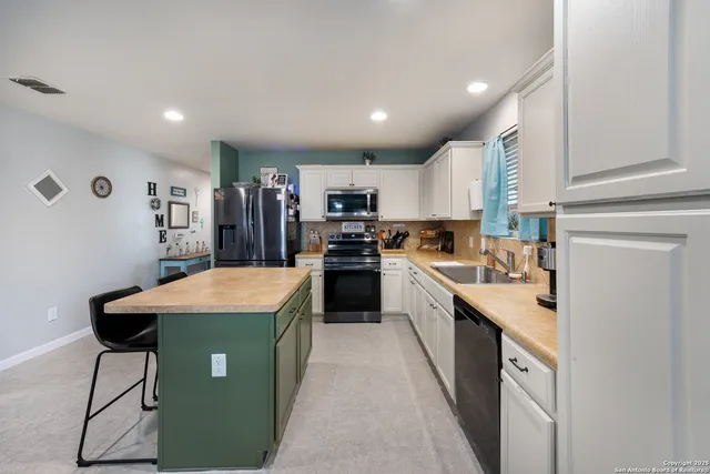 a kitchen with kitchen island stainless steel appliances sink cabinets and stove