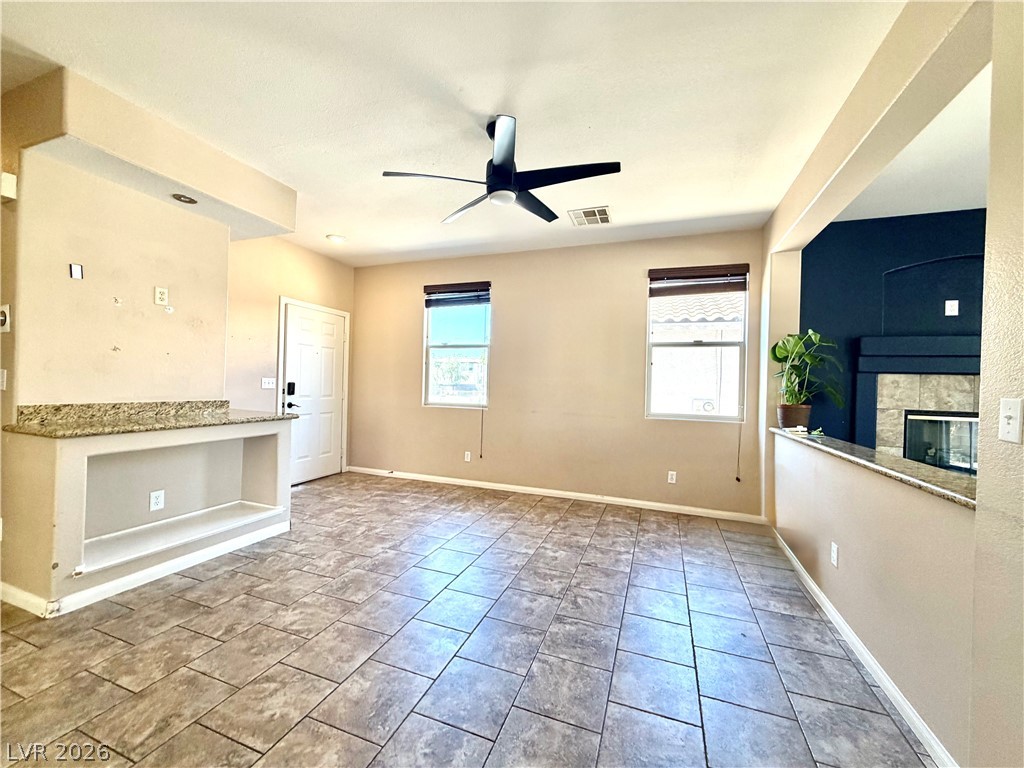 An inviting open-plan living area features durable tile flooring and a cozy fireplace.