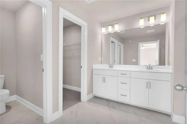 a spacious bathroom with a granite countertop sink a toilet and a mirror