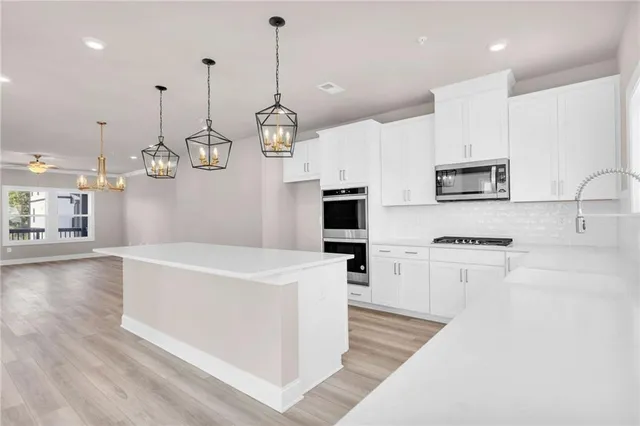 a large kitchen with kitchen island a stove a sink a center island and wooden floor