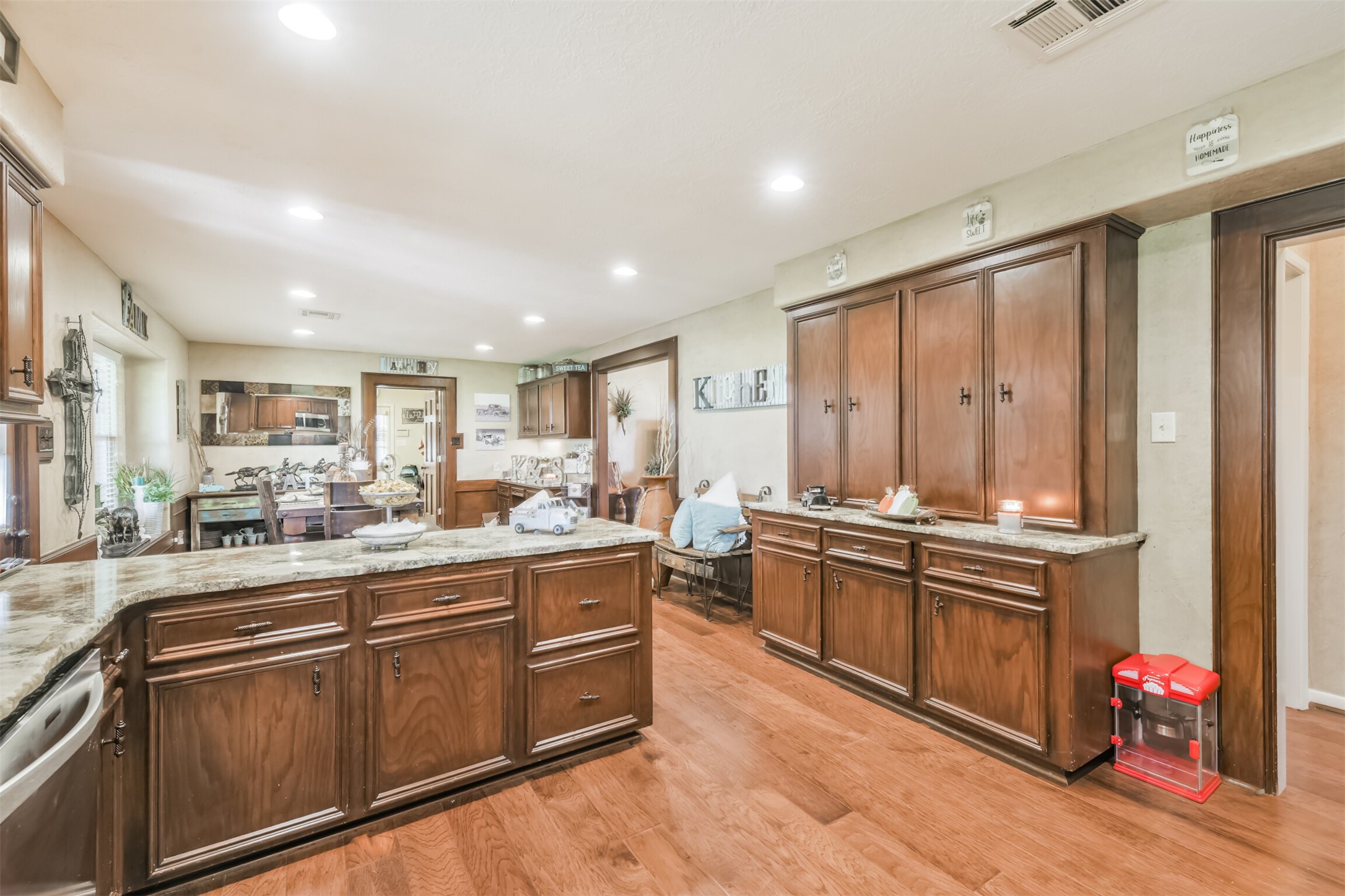 307 West Hufsmith Road Tomball, TX 77375 - Photo 18 of 44 Spacious kitchen with rich wooden cabinetry, granite countertops, and recessed lighting, seamlessly leading into a cozy dining area.