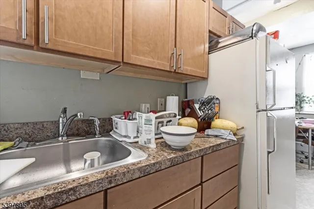 a kitchen with granite countertop a sink a refrigerator and cabinets