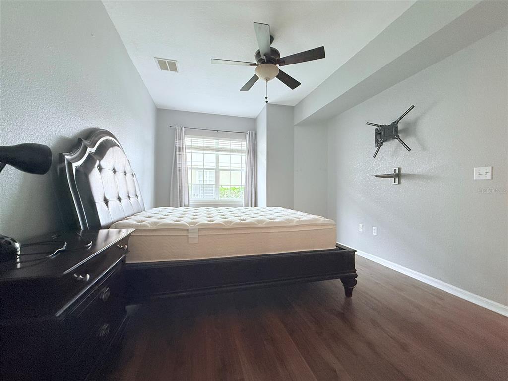 100 Turpial Way, Unit 107 Melbourne, FL 32901 - Photo 7 of 16 a bed sitting in a room next to a window and a chandelier