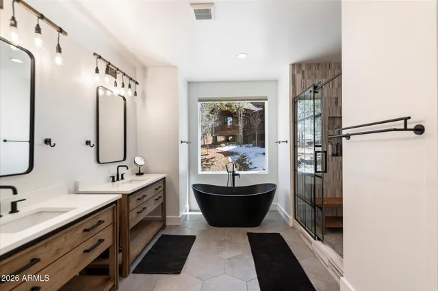 a bathroom with a double vanity sink a mirror a bathtub and shower
