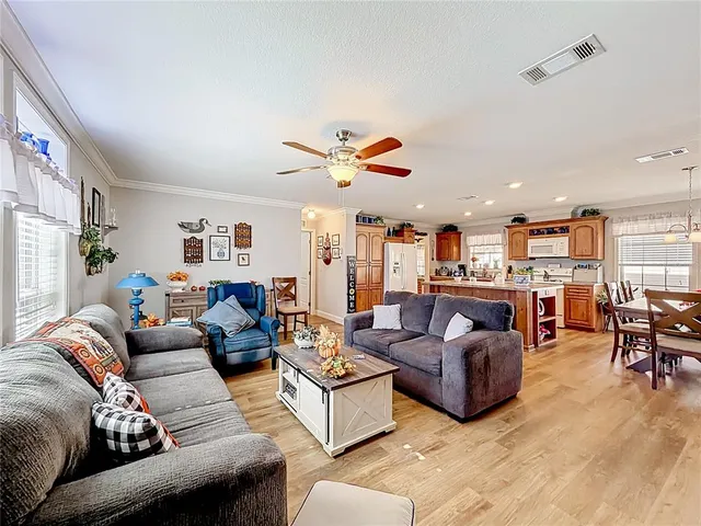 a living room with furniture kitchen view and a large window
