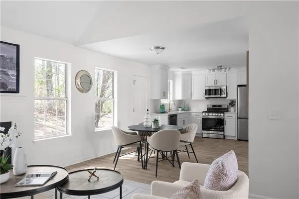a kitchen with granite countertop lots of white cabinets a dining table and chairs