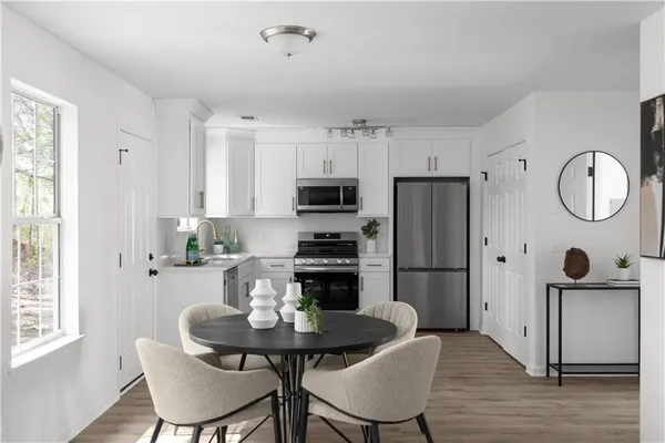 a kitchen with stainless steel appliances granite countertop a dining table chairs refrigerator and sink