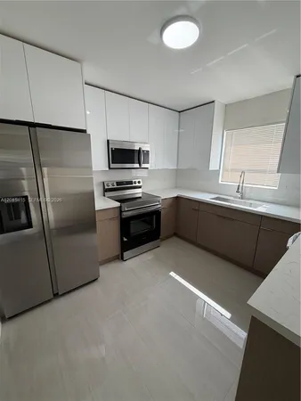 a kitchen with stainless steel appliances a sink a stove a microwave a refrigerator a sink and dishwasher
