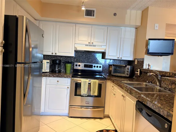 a kitchen with stainless steel appliances granite countertop a stove a refrigerator and a sink