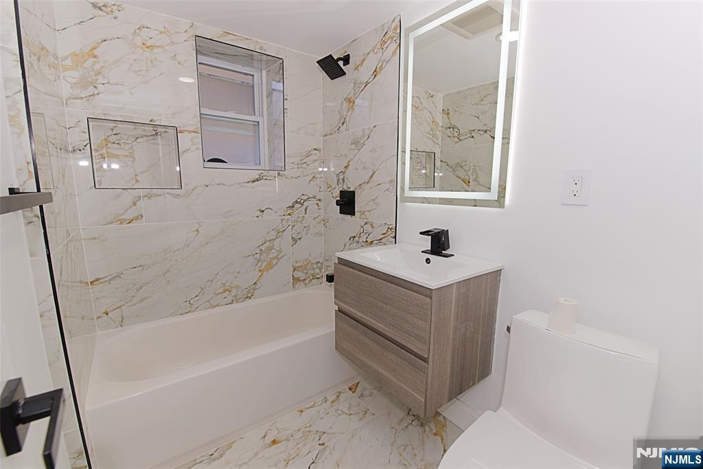 401 Undercliff Avenue Edgewater, NJ 07020 - Photo 23 of 50 a bathroom with a sink mirror vanity and a bathtub